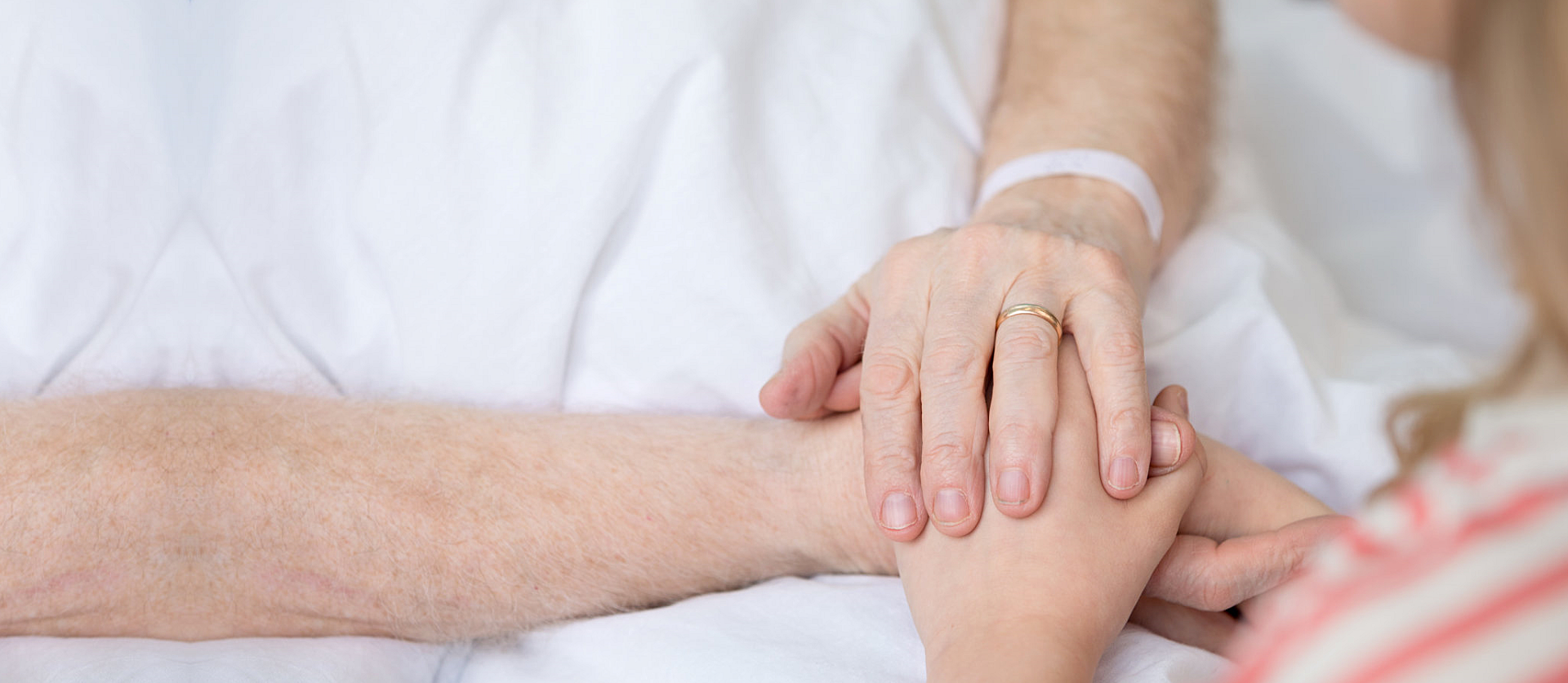 close up of patient grandfather and child holding hands in hospital bed