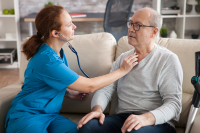 female nurse using stethoscope to a senior man